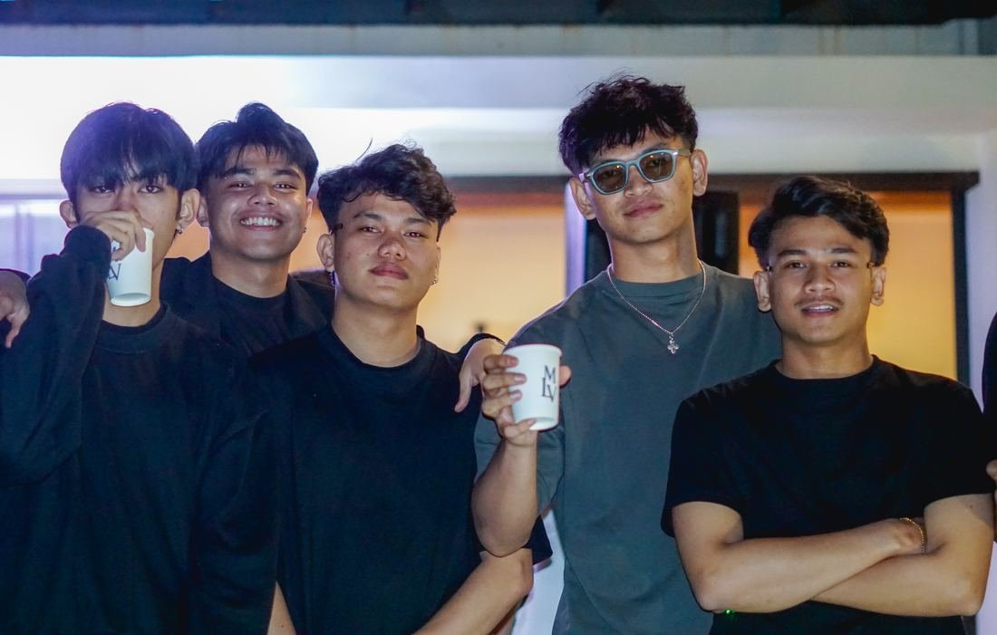 Lima cowok berbaju hitam pose bareng, dua pegang gelas bertuliskan MLV