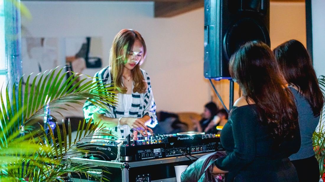DJ perempuan berbaju garis hitam putih memainkan controller Pioneer DJ